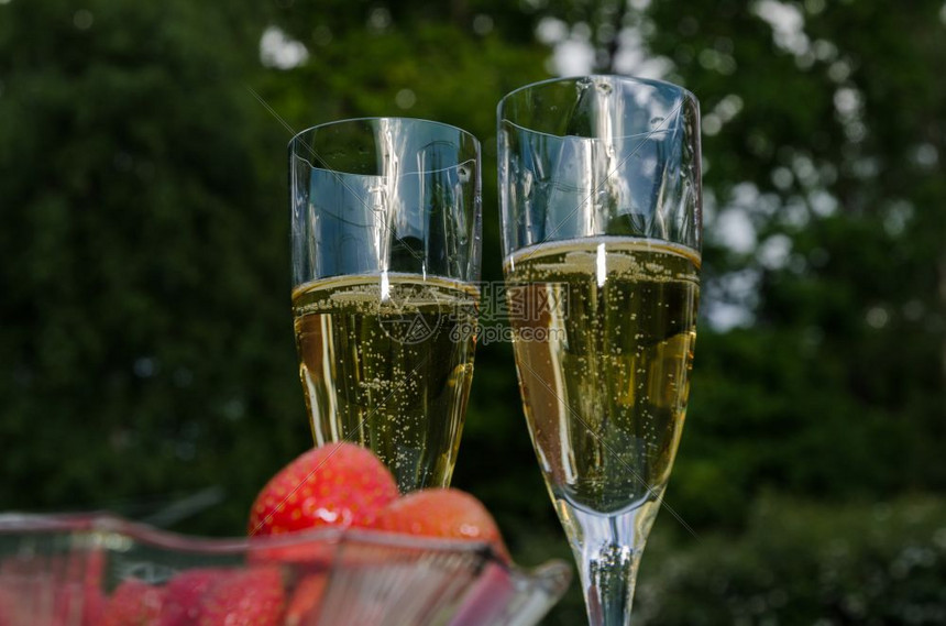 爱两杯外边有香槟的酒杯和一碗模糊的前台布满草莓景鸡尾酒图片