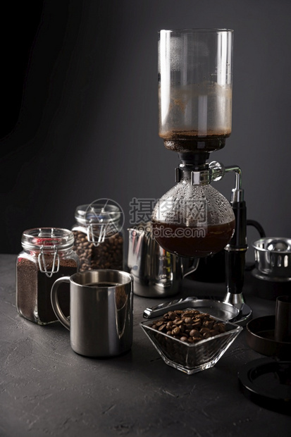 热玻璃虹吸管混凝土咖啡机也称为真空锅抽水或催眠咖啡机金属杯和生锈黑石桌上的烤咖啡豆图片