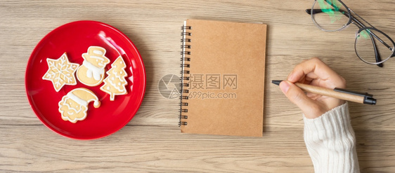 时间妇女手写笔记本在表格Xmas新年快乐目标决议清单战略和计划概念上用圣诞饼干写字刨冰日历图片
