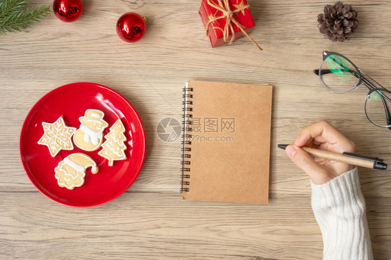 前夕妇女手写笔记本在表格Xmas新年快乐目标决议清单战略和计划概念上用圣诞饼干写字日记天图片