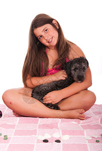 穿着泳衣的黑发笑脸少女在海滩上穿泳装的女孩与她小船狗工作室用粉色毛巾和白背景孤立的小石头鹅卵幸福青少年图片