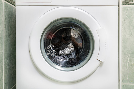 纺纱湿的家庭准备在洗衣机玻璃中的脏衣服便装箱图片