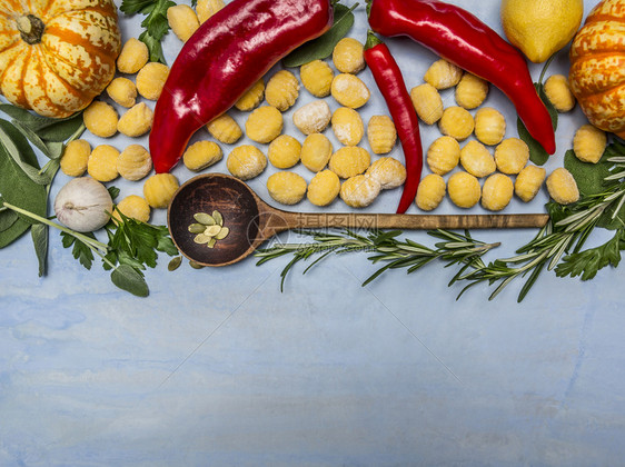南瓜格诺奇配有木勺秋叶水果蔬菜和草药蓝木本底色的番茄生图片