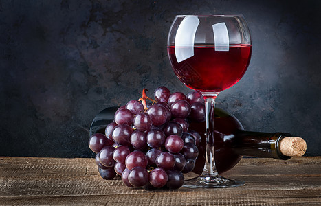 酒杯红葡萄和瓶子放在木制桌上酒瓶在黑暗背景赤霞珠庆典优质的图片
