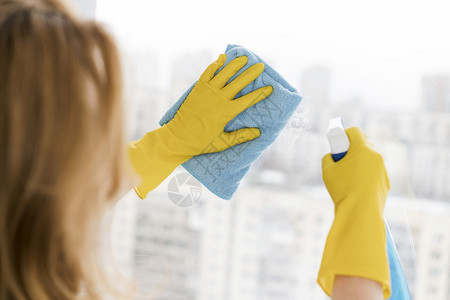 卫生黄色的在职妇女用抹布打扫窗户图片