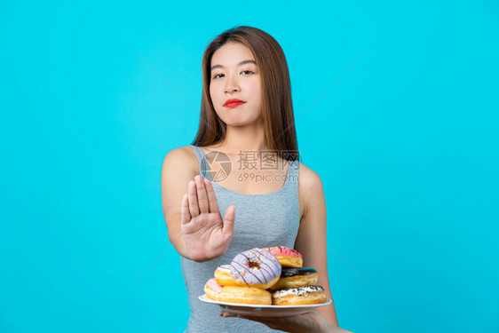 积极的自信有吸引力亚洲年轻女不与甜圈就孤立的蓝色背景体重减少和避免垃圾食品用于饮和健康概念复制空间和工作室等采取行动具有吸引力的图片
