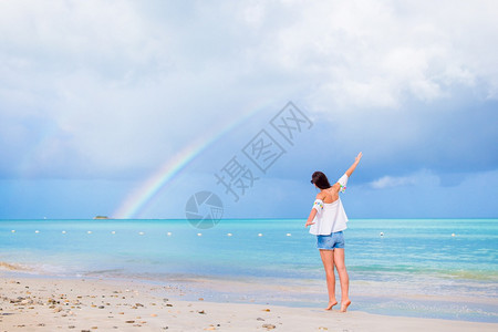 水快乐的美丽女人在海滩上美丽的彩虹在海面上美丽的幸福女人在海滩上美丽的彩虹在海面上图片