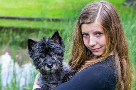 舍内维尔在绿公园携带手持黑狗的金蓝caucasian少女吸引人的白种图片