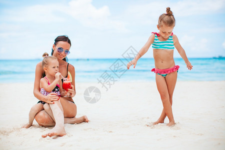 小女孩和年轻母亲在热带白沙滩玩耍图片