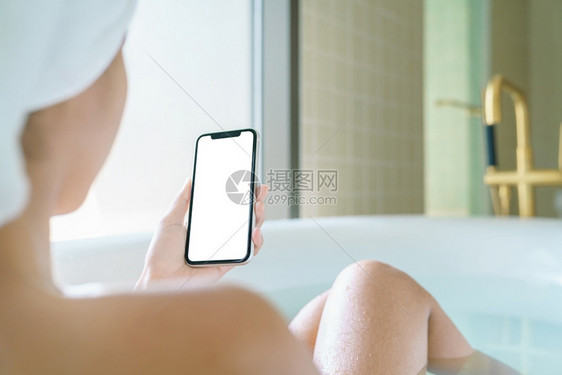 干净的浴室女用手机空白屏幕显示清晨用智能手机在浴缸里放松展示图片