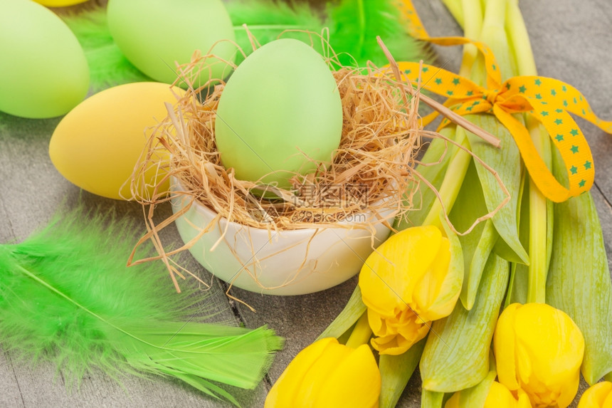 花以东鸡蛋和黄郁金香在木制桌子上的照片传统图片