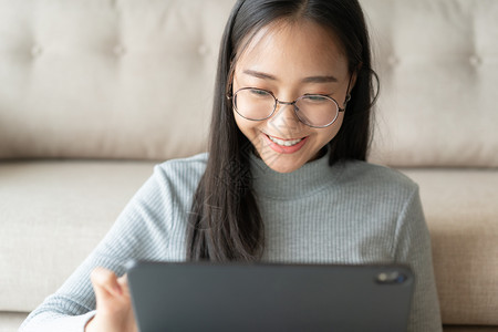 现代的亚裔女孩在家里工作时笑着的亚洲女孩在她家里工作的时候她会微笑着说快乐的天图片