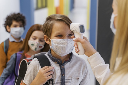 女孩教师用医疗面具检查学生温度校的体课堂注册图片