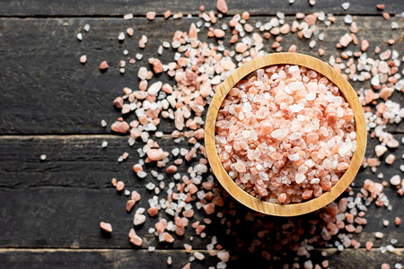 粒状水平的放在黑木喜马拉雅盐上的木碗中粉色盐治疗图片