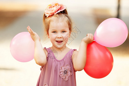 快乐的带着多彩气球笑和扮演小女孩的肖像喜悦孩子积极模仿户外人类图片