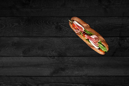 黑色木桌上的三明治图片