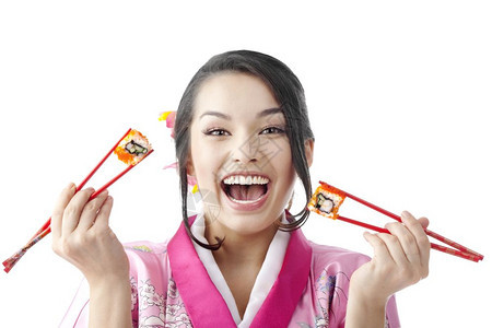 鱼子酱头发脸美丽的日本年轻女子用两对棍吃寿司的肖像在白色背景上穿着传统喜莫诺服饰她们穿着白色背景的衣服图片