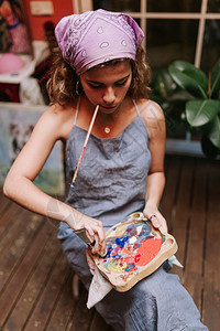 专业女艺术家在工作室画布上用刷子在她的嘴里画室内镜头艺术专业图片