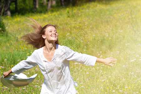 稻草保持白种人快乐的年轻女子带着白帽在衣绿草地上奔跑图片