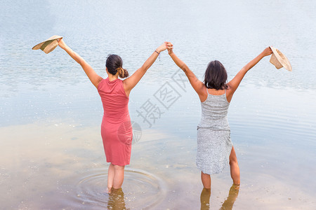 表示两个快乐的朋友们在湖水中站一起欢喜乐趣图片