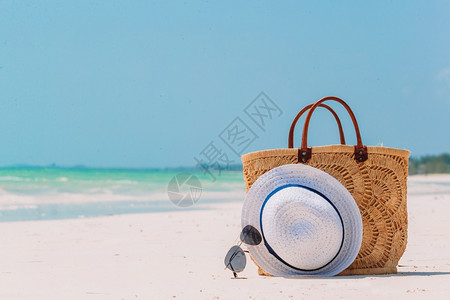 白色沙滩上的草袋帽子和太阳镜图片