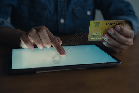 正在做现代的男手在网上用信卡买入触摸屏幕男子使用平板电脑并进行在线交易男人正在使用平板电脑和进行在线交易支付图片