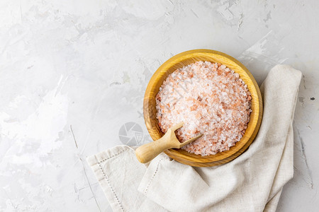 美丽有质感的调味品粉红喜马拉雅岩盐放在碗中勺子浅背景上图片
