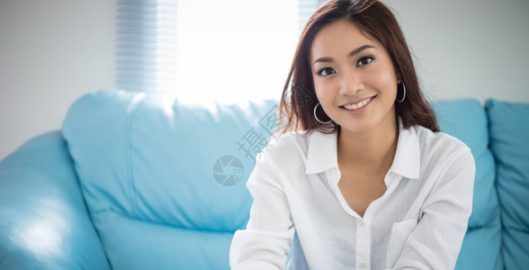 在线的保持坐沙发上着放松的亚洲妇女她在家里笑着开心聪明的图片