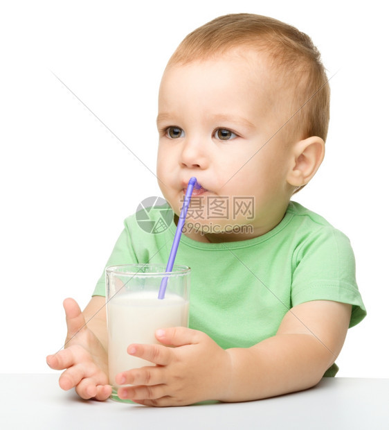 保持衬衫一顿饭可爱的小男孩坐在桌边子上用稻草喝牛奶在白上面被孤立图片
