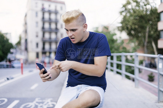 城市的年轻十几岁男孩在使用手机时坐在街上身着金发大爆炸的女孩刘海户外图片