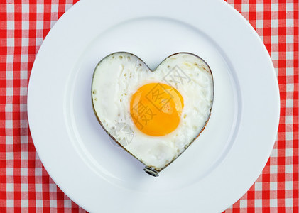 细胞盘子给爱人吃早餐在旧桌布上烤成心形的炸鸡蛋红色图片