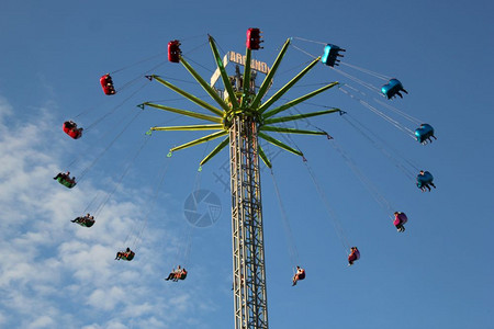 娱乐夏天人们在蓝色的空中乘着转动的发风轮飞翔公平的图片