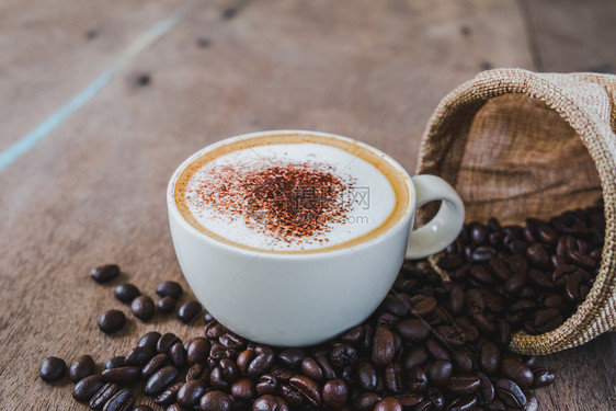 新鲜咖啡店口袋中豆和木桌背景的咖啡杯香气图片