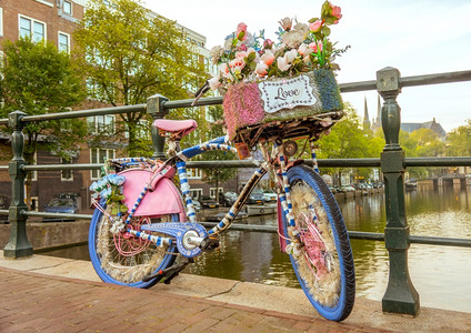 城市传统栏杆在阿姆斯特丹运河A花朵装饰的自行车上挂着爱标志的荷兰云色早晨停在桥墙围栏Love双轮车停在阿姆斯特丹运河大桥的铁路上图片