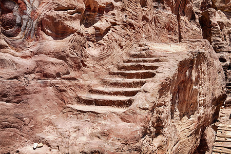 一小连串的石头步骤作为一座旧楼梯沿着悬崖的侧面走向位于约旦南部古代城市彼得拉之地的乌恩墓皇家联合国教科文组织路图片