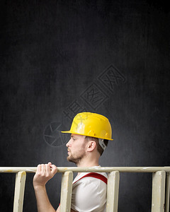 行业帽子一名持有梯的建筑工人侧面观景象一名带有梯子的建筑工人纵向形象承包商图片