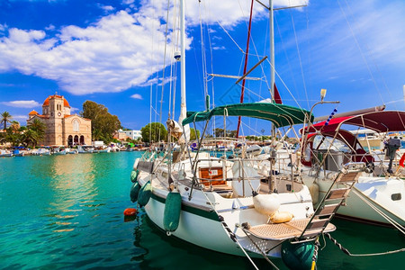晴天著名的旅游希腊阿埃吉纳岛萨龙海湾有帆船和教堂图片