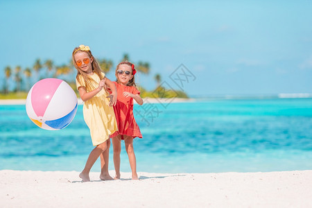 夏天可爱的小女孩在沙滩上玩球小可爱的女孩在沙滩上玩空气球孩子们在海边玩得很开心运动海洋图片