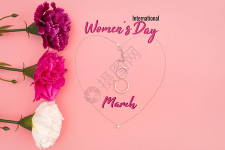 快乐的国际妇女节花朵和心形项链粉红背景的鲜花和心形项链钻石刻字图片
