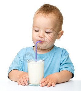 人类青年可爱的小男孩坐在桌边子上用稻草喝牛奶在白上面被孤立保持图片