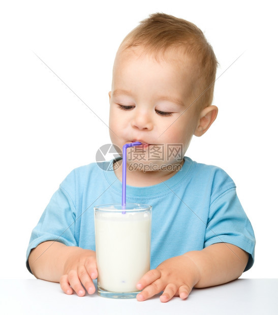 人类青年可爱的小男孩坐在桌边子上用稻草喝牛奶在白上面被孤立保持图片