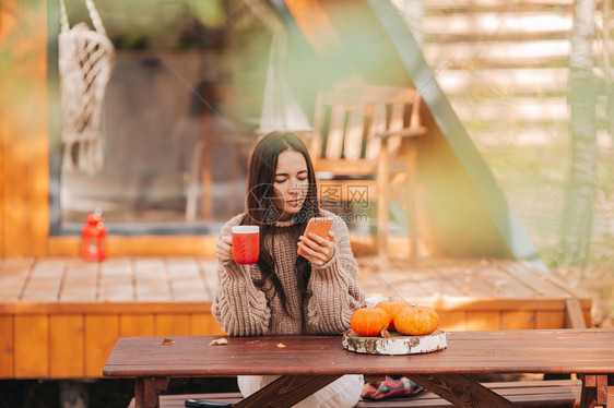 休息快乐的年轻女人喝着咖啡坐在户外木制桌边的咖啡欢乐年轻女人闲暇白日梦图片
