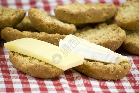 新鲜烤面包卷白布和红面上加芝士饼木制的可口面包店图片