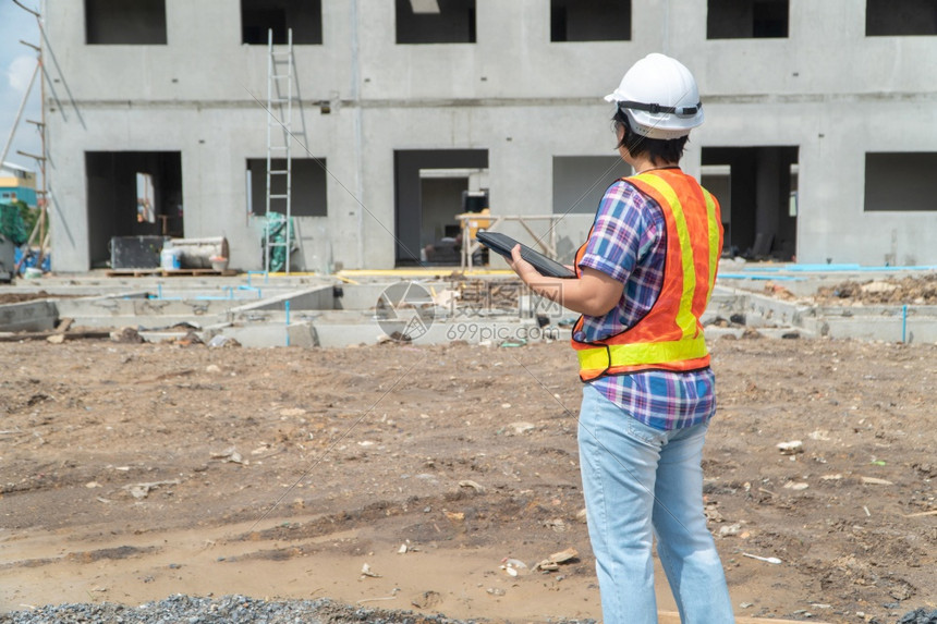 项目工业的在建筑地上站着时用平板头戴盔的亚洲女建筑工肖像以背景概念为构筑工程想建学图片