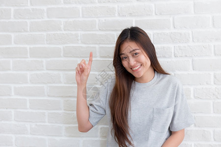 女微笑美丽的亚洲女孩指着在背景墙壁上复制空间的亚洲美女白妇笑脸快乐手指图片