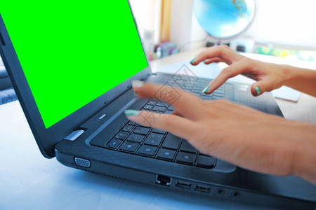 工作场所桌面妇女在办公室用笔记本电脑工作时手握绿色屏幕打字图片