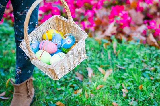 孩子拿着篮带东西鸡蛋的篮子在孩手里把满了彩色复活节鸡蛋的篮子花园草传统图片