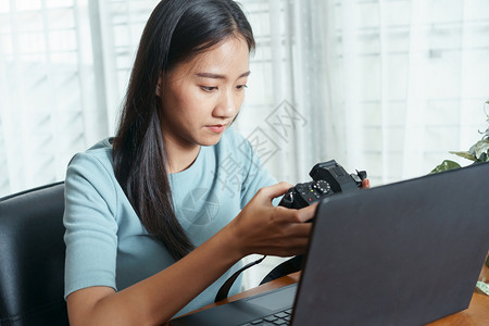 人们亚洲妇女使用数码相机并将笔记本电脑放在移动办公室的桌子上漂亮照片图片