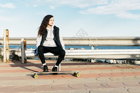 木板户外青少年女坐在长凳上双脚海面的长板上幸福图片