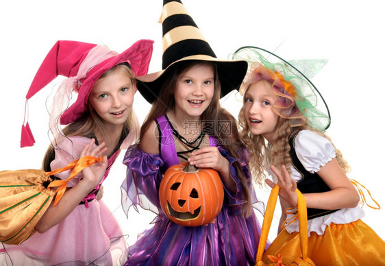 摆姿势三个美丽的微笑小女孩长发在彩色服装中看着镜头与诡计或处理袋和杰克奥斯柯绿灯狂欢图片